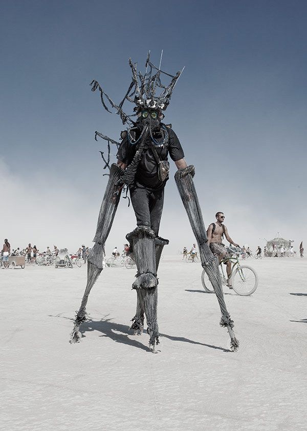 Участник Burning Man на ходулях в маске. Пустыня Блэк-Рок